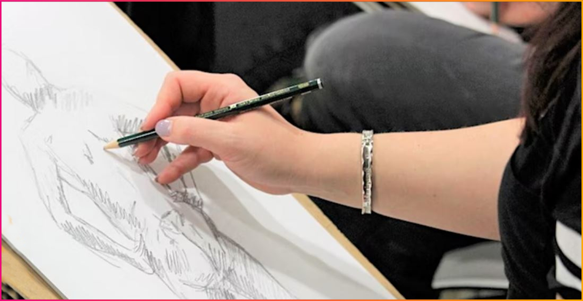 young artist holding a pencil drawing the human form on paper