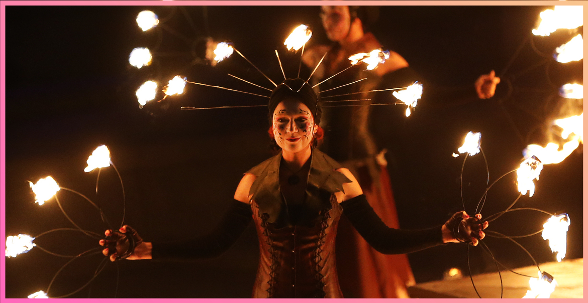 Two women performers holding batons on fire