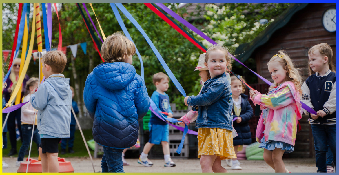 A class of pre-school children holding a ribbon in a circle.