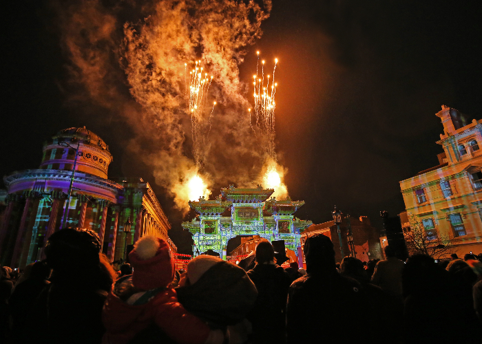 Picture of Chinese arch in Liverpool at night surrounded by projections and pyrotechnics and people watching on