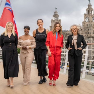 A line-up of women pose for a photo in front of the Royal Liver Building.