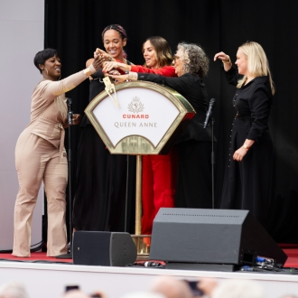 On stage for the naming ceremony of Queen Anne, five women pull the lever to name the ship.