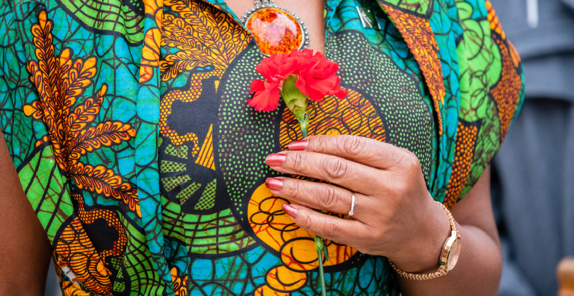 A person clutching a red flower to their chest