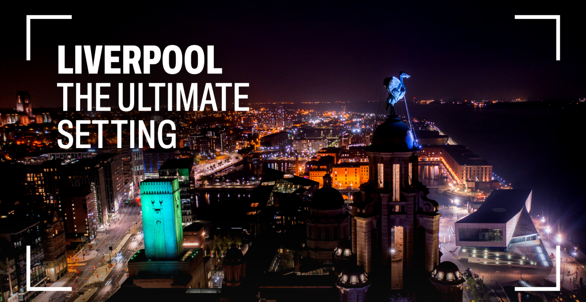 A drone shot of Liverpool's iconic city scape at night with a Liver Bird in view. Whte text reads "LIVERPOOL THE ULTIMATE SETTING"