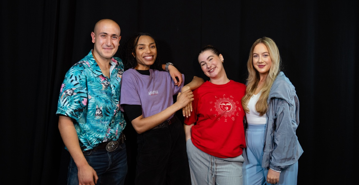 A group of four people stood together against a black background.