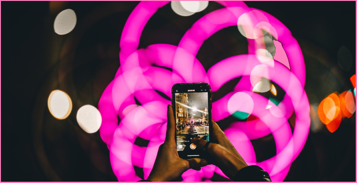 a person taking a photo of pink illuminated circles