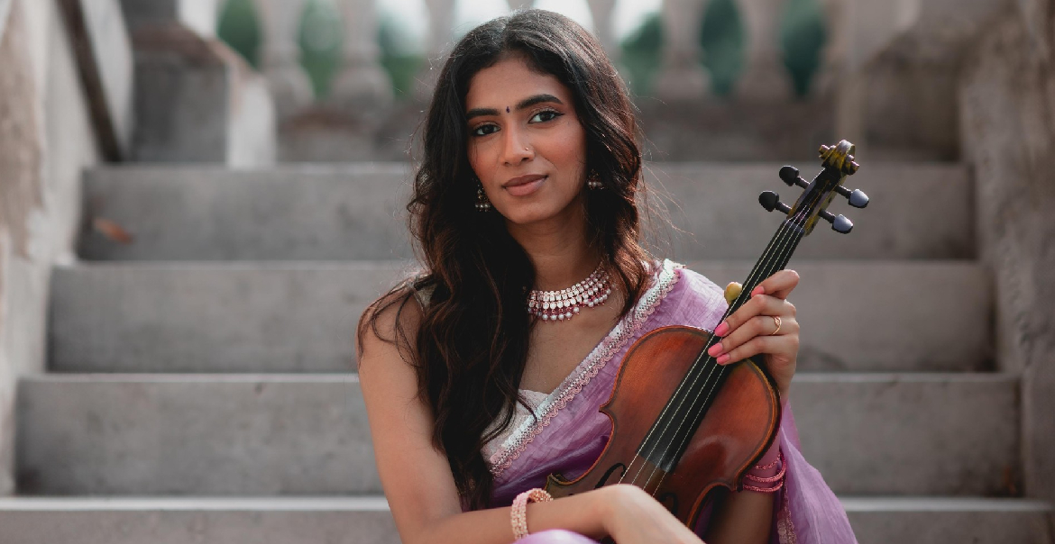 A woman holding a violin sitting on outdoor steps