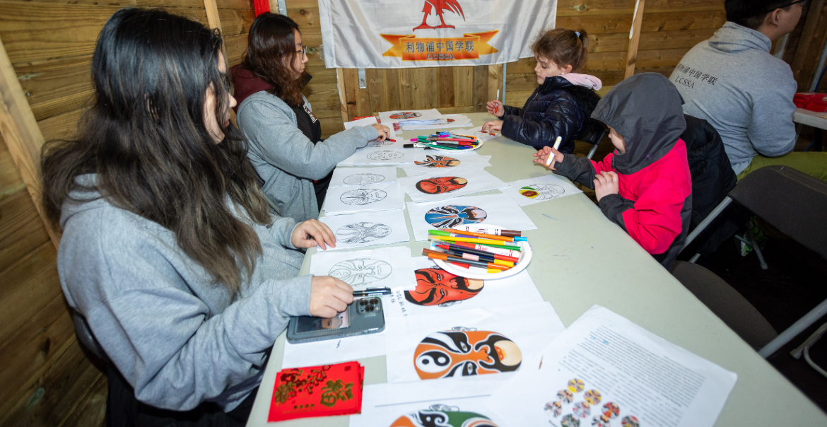 Four young people sat around a table taking part in a traditional Chinese arts workshop