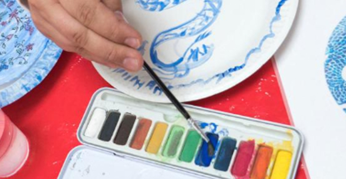 A close up image of a person painting a plate