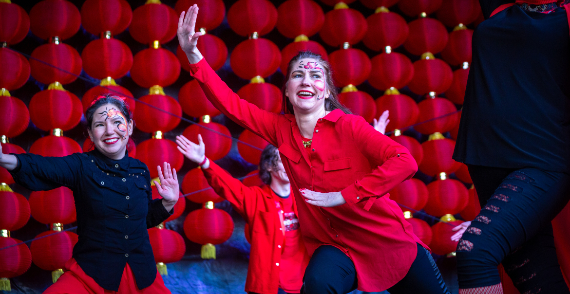 People performing on stage at Chinese New Year event with red lanterns behind them