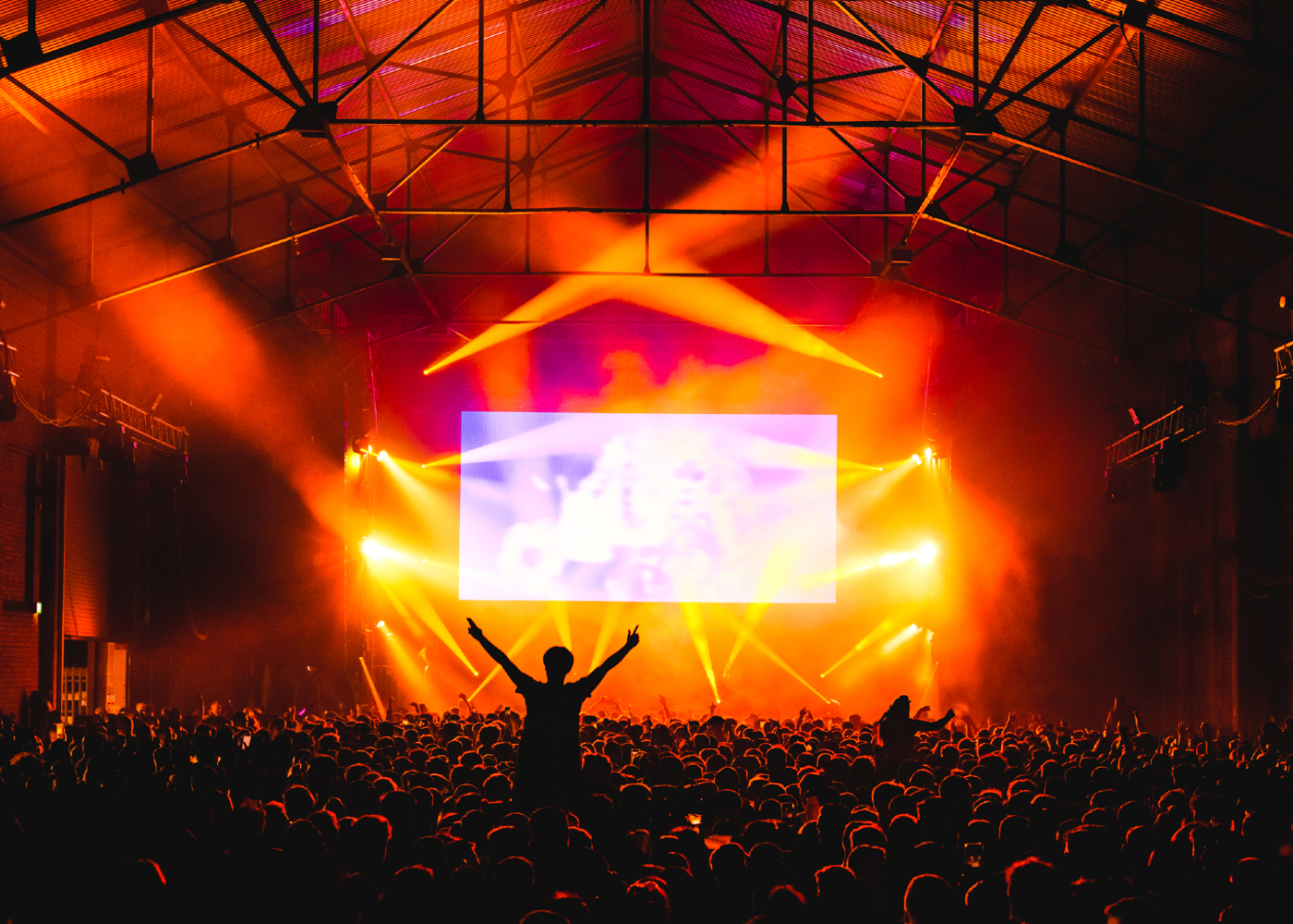 group of people enjoying a club night in a warehouse in Liverpool with a stage lit up with lights