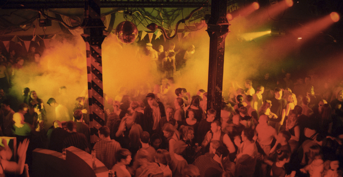 People dancing in a club under a yellow-ish light