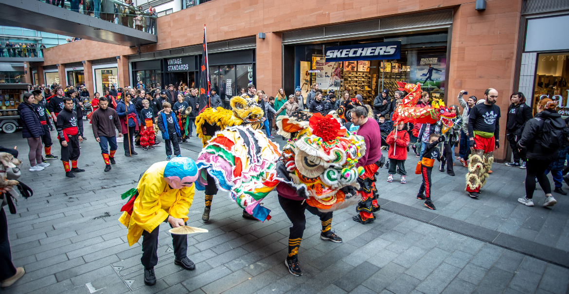 An image of a traditional dragon and lion parade for Chinese New Year taking place in a busy high street