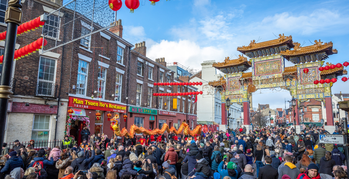 An image of Chinatownin Liverpool with the archvisible in the background. Lagre crowds fill the streets in celebration of Chinese New Year