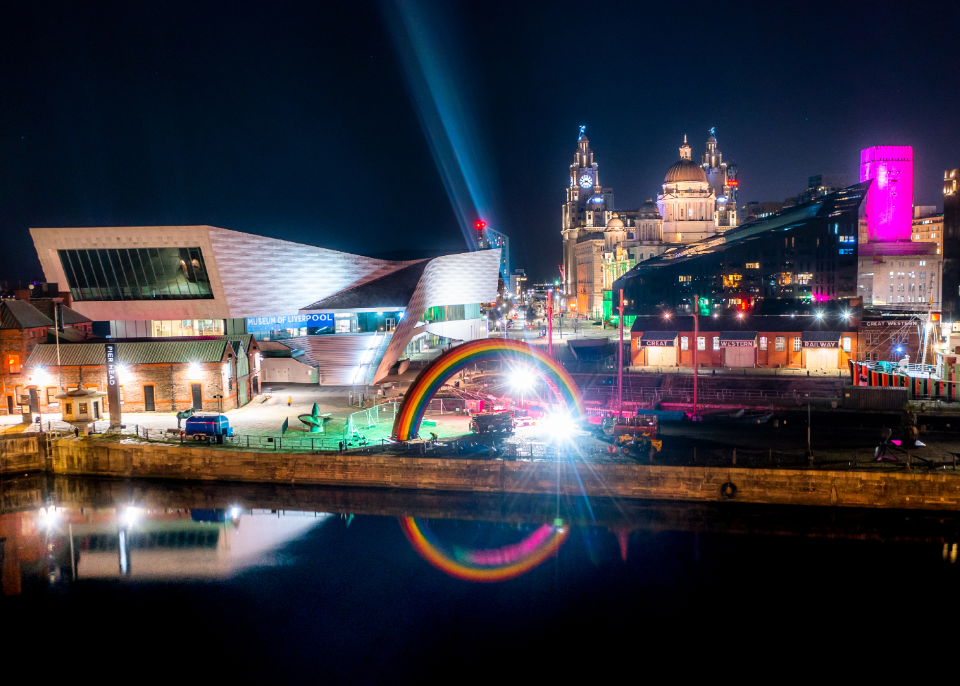 Picture of the Liverpool waterfront at night with a rainbow light installation reflected in Canning Half Tide Dock