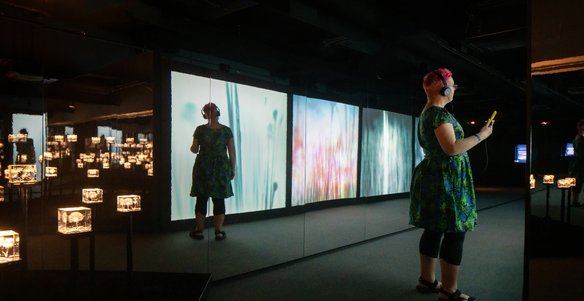 People exporing an interactive museums with displays of illuminated images in a dimly lit room