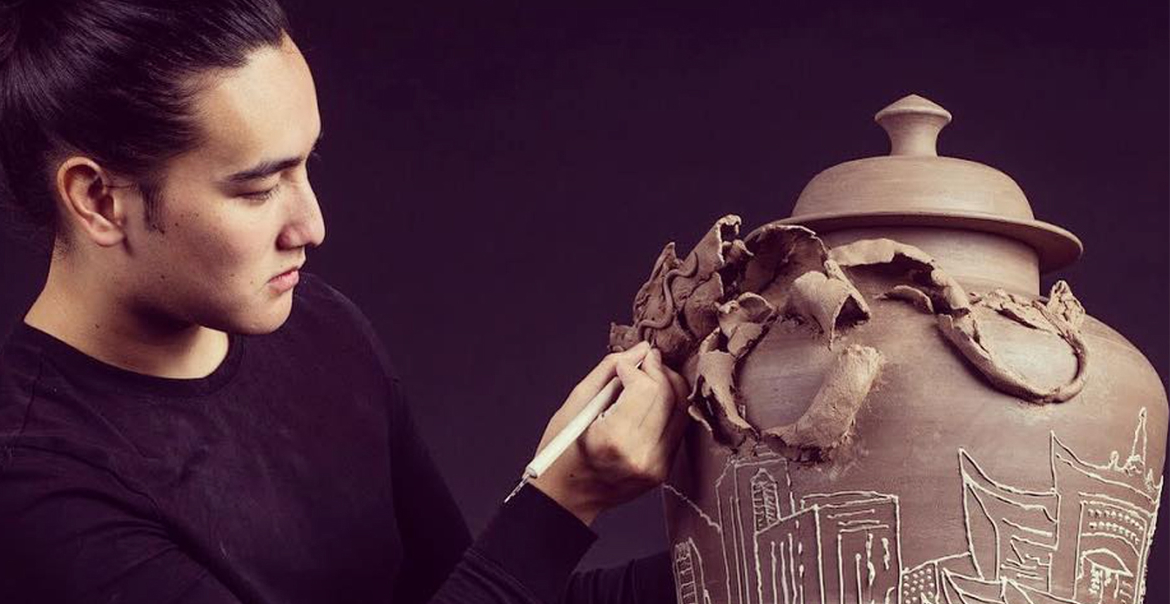 A man sculpting a large clay vase